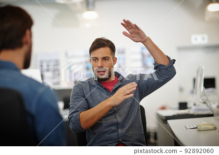 We should be thinking much bigger now. Shot of a young businessman gesturing while explaining something to his colleague in the office. We should be thinking much bigger now. Shot of a young businessman gesturing while explaining something to his colleague in the office. 92892060