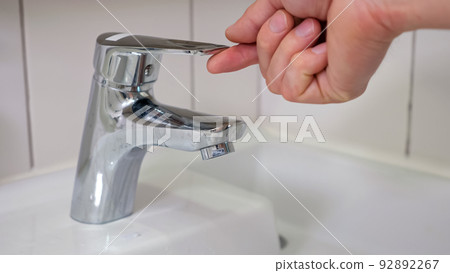Male hands turn on water faucet and water quickly flows Male hands turn on water faucet and water quickly flows 92892267