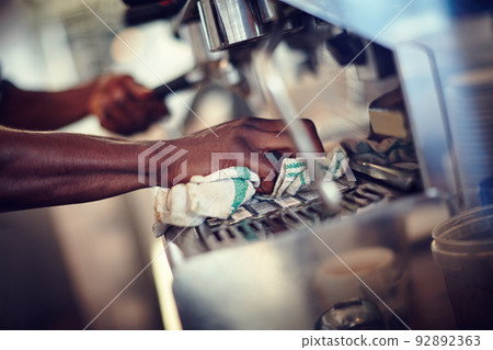 Taking good care of his espresso machine. Closeup shot of a barista cleaning an espresso machine at a cafe. 92892363
