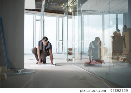 Making sure everything is in place. Young contractor checking his plans on a construction site indoors. Making sure everything is in place. Young contractor checking his plans on a construction site indoors. 92892569