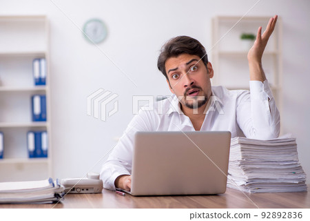 Young male employee and too much work in the office Young male employee and too much work in the office 92892836