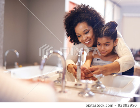 Lets get them good and clean. Cropped shot of a mother and daughter washing their hands at the bathroom sink. Lets get them good and clean. Cropped shot of a mother and daughter washing their hands at the bathroom sink. 92892950