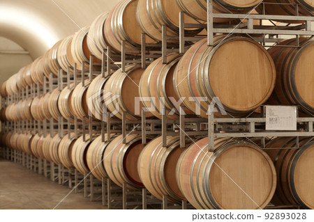 Mass producing wine. Stacked barrels of wine at a wine distillery. 92893028