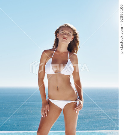 Tanned beauty. Cropped portrait of an attractive young woman standing outside in her bikini. 92893106