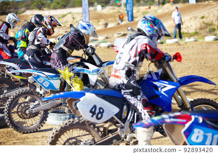 Its a race to the finish. Rear view of a group of motocross riders waiting for a race to start. 92893420