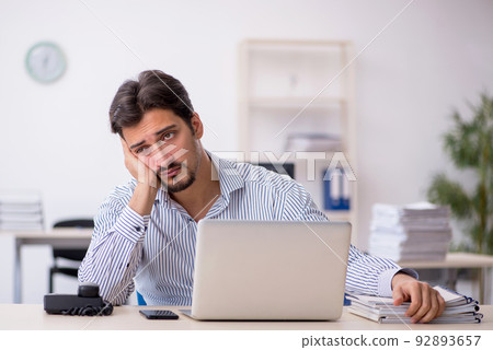 Young male employee and too much work in the office Young male employee and too much work in the office 92893657
