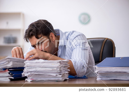 Young male employee and too much work in the office Young male employee and too much work in the office 92893681