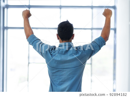 I did it once again. Rearview shot of an unrecognizable businessman celebrating with his arms raised in a modern office. I did it once again. Rearview shot of an unrecognizable businessman celebrating with his arms raised in a modern office. 92894182
