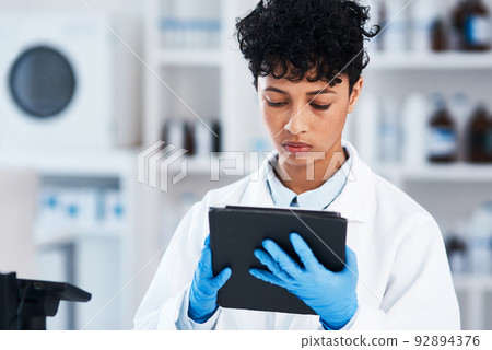 Digitising some of her work for more efficient results. Shot of a young scientist using a digital tablet in a lab. 92894376