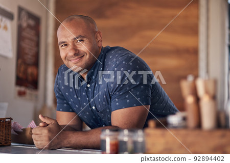 Ready to serve my customers. Portrait of a cheerful young coffee barista leaning on the counter of his coffee truck to serve customers outside during the day. 92894402