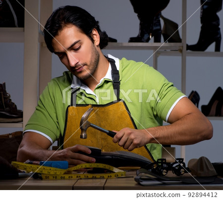 Young shoemaker in workshop at night 92894412