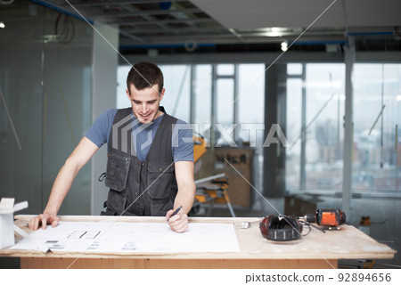 Making some quick changes. Young architect working on his plans while at a construction site. 92894656