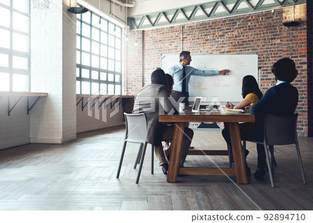 Directing his team through the plan. Shot of a mature businessman giving a presentation to his colleagues in an office. Directing his team through the plan. Shot of a mature businessman giving a presentation to his colleagues in an office. 92894710