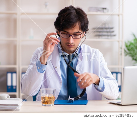 Young male doctor drinking in the office Young male doctor drinking in the office 92894853