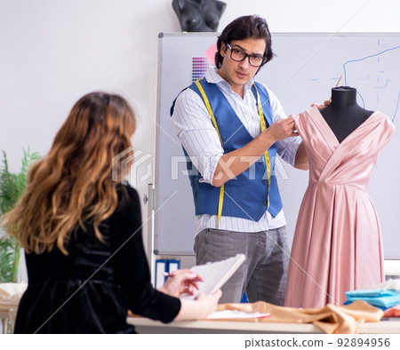 Young male tailor teaching female student 92894956