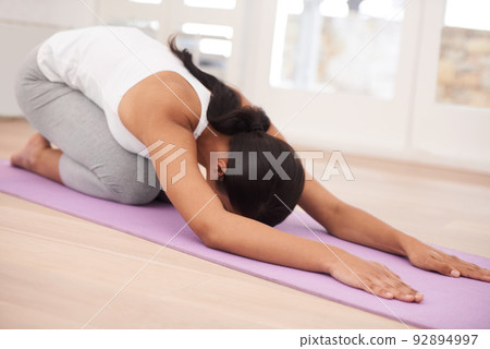 Pilates keeps me lean. A young woman exercising in her home. 92894997