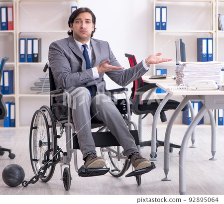 Young handsome employee in wheelchair working in the office Young handsome employee in wheelchair working in the office 92895064