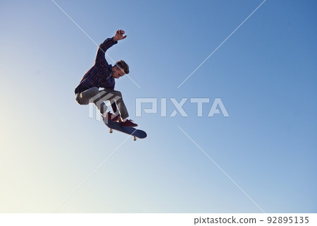 A rad day at the skate park. A young man doing tricks on his skateboard at the skate park. 92895135