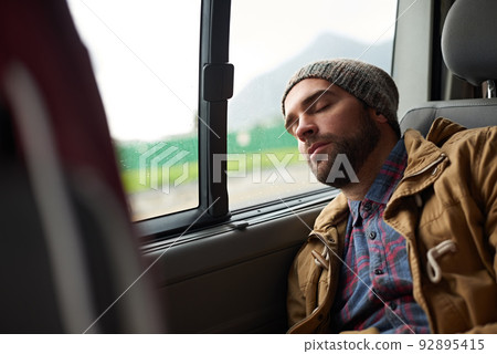 Exhausted after a long days travels. Shot of a handsome asleep in the back seat of a travelling vehicle. Exhausted after a long days travels. Shot of a handsome asleep in the back seat of a travelling vehicle. 92895415