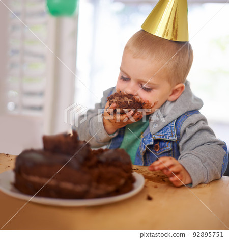 Who left him alone with the cake. Cropped shot of a young boy eating his birthday cake before the party. Who left him alone with the cake. Cropped shot of a young boy eating his birthday cake before the party. 92895751