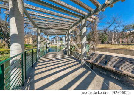 Concrete walkway with pergola and bench near the river at San Antonio, Texas 92896003