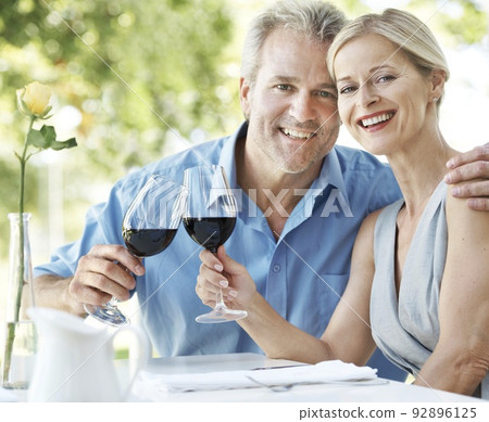 Still in love and committed to each other. Happy mature couple toasting their love with two glasses of wine while outdoors. Still in love and committed to each other. Happy mature couple toasting their love with two glasses of wine while outdoors. 92896125