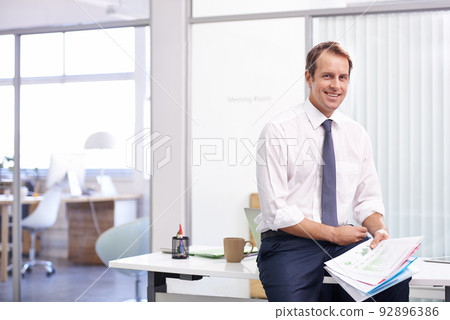 Happy friday finance review. Portrait of a handsome young businessman reading through documents in his office. Happy friday finance review. Portrait of a handsome young businessman reading through documents in his office. 92896386