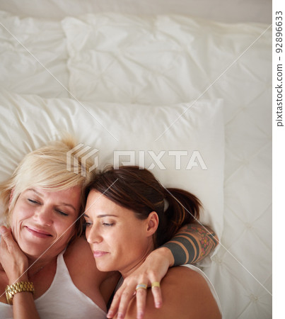 Tender morning moments. High angle shot of a loving lesbian couple lying in bed. 92896633