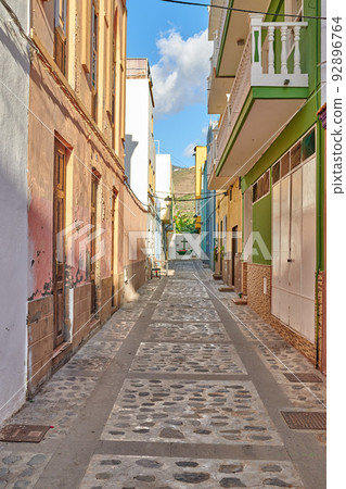 Empty cobbled street in a rural European tourist town. A quiet narrow alley way with colorful apartment buildings or houses. Hidden side street with traditional architecture in Santa Cruz de La Palma 92896764