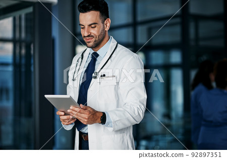 Book an online consult with the medical fields best. Shot of a young doctor using a digital tablet in a hospital. 92897351
