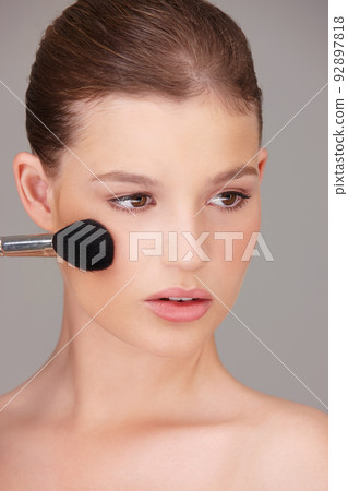 Enhancing her natural beauty with a touch of blush. Studio shot of a beautiful woman applying blush to her cheeks. 92897818