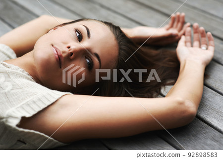 Shes a natural beauty. An attractive young woman lying on her porch. Shes a natural beauty. An attractive young woman lying on her porch. 92898583