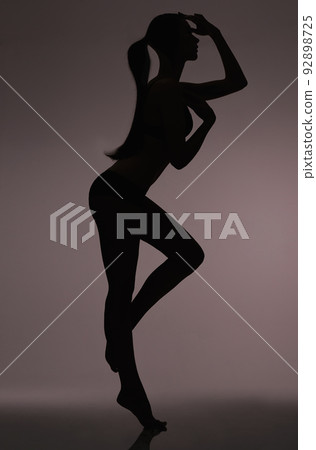 Silhouetted beauty. Studio silhouette of a beautiful woman in lingerie against a gray background. 92898725