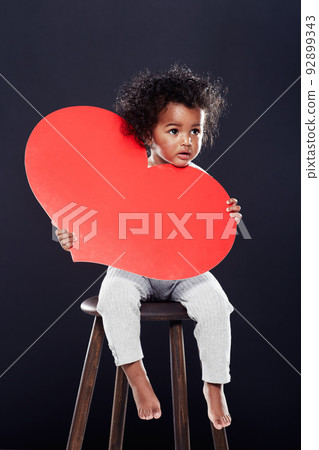 You have my heart. Studio shot of a cute little girl holding a big heart isolated on black. 92899343