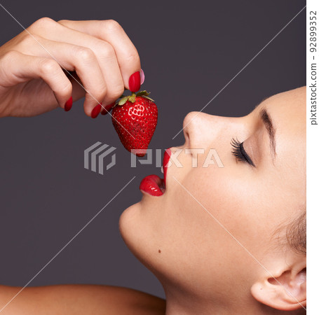 Sensuous strawberries. Closeup portrait of a beautiful young woman with strawberry in her mouth. 92899352
