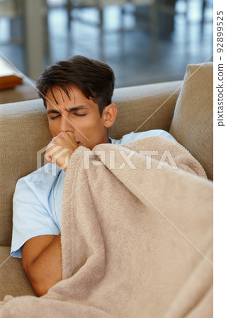 No more staying out late for me. Cropped shot of a young man coughing. 92899525