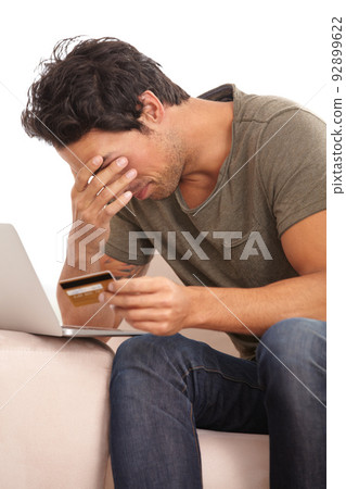 Feeling the credit crunch. A young man with his head in his hand looking upset while holding his credit card. Feeling the credit crunch. A young man with his head in his hand looking upset while holding his credit card. 92899622