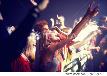Enjoying the music. A group of people standing with their arms raised at a concert. Enjoying the music. A group of people standing with their arms raised at a concert. 92899715