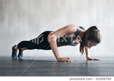 Shes taking this workout to the next level. Shot of a woman doing pushups at the gym. Shes taking this workout to the next level. Shot of a woman doing pushups at the gym. 92899769