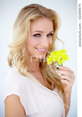 Just so ladylike. Portrait of a pretty young woman holding a yellow flower - Isolated on white. 92899974
