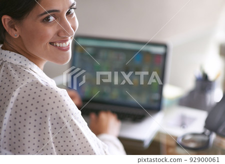 Working with a smile. A young woman happily working at her computer. Working with a smile. A young woman happily working at her computer. 92900061