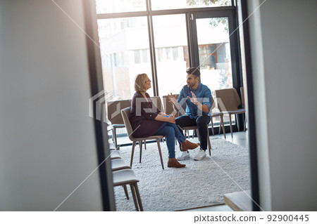 Young businessman talking to his therapist after a therapy meeting at a psychology office for mental health problems. Male employee having a discussion with a mature woman in a modern boardroom 92900445