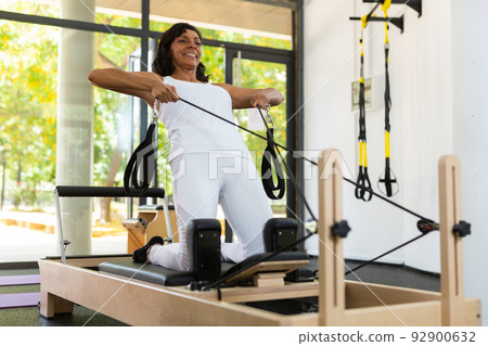 Woman doing exercises on pilates reformer 92900632