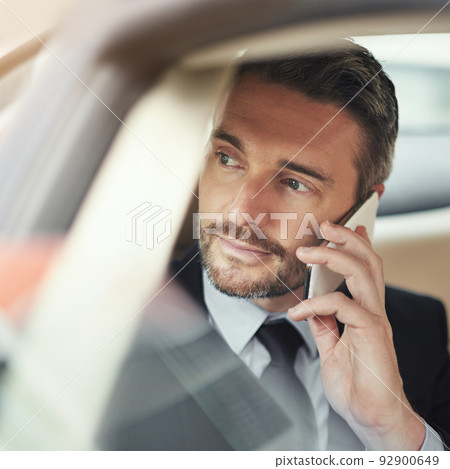 Getting more out of his commute with wireless technology. Shot of a businessman using his phone while traveling in a car. Getting more out of his commute with wireless technology. Shot of a businessman using his phone while traveling in a car. 92900649