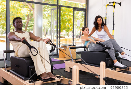 Attentive African American man practicing pilates on reformer Attentive African American man practicing pilates on reformer 92900823