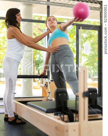 Girl doing exercises in pilates gym with female instructor 92900901