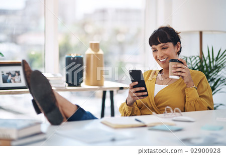 Coffee and technology go hand in hand. Cropped shot of an attractive young businesswoman sitting with her feet up in her office and using her cellphone. Coffee and technology go hand in hand. Cropped shot of an attractive young businesswoman sitting with her feet up in her office and using her cellphone. 92900928
