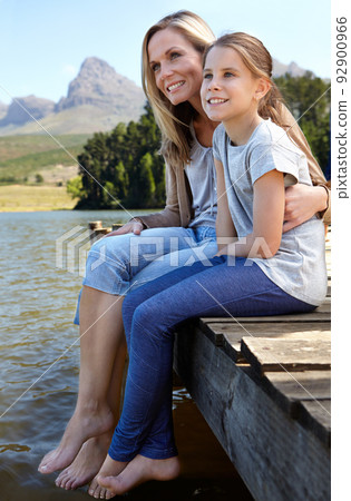 Mom will always be there. Full length shot of a mother and daughter sitting on a pier at the lake. 92900966
