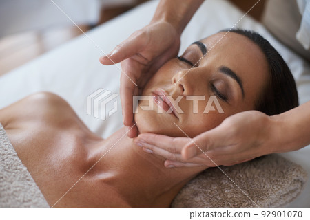 Theres no better way to relax. Shot of an attractive woman enjoying a face massage. 92901070