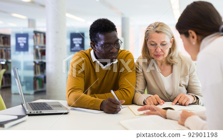 Students sitting in library, working with professor Students sitting in library, working with professor 92901198